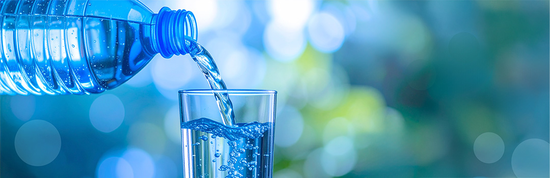 Wasser wird aus einer Flasche in ein Glas gegossen