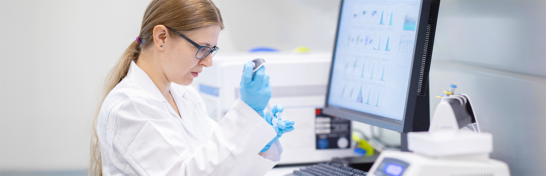 Forscherin sitz vor Monitor und testet eine Wasserprobe